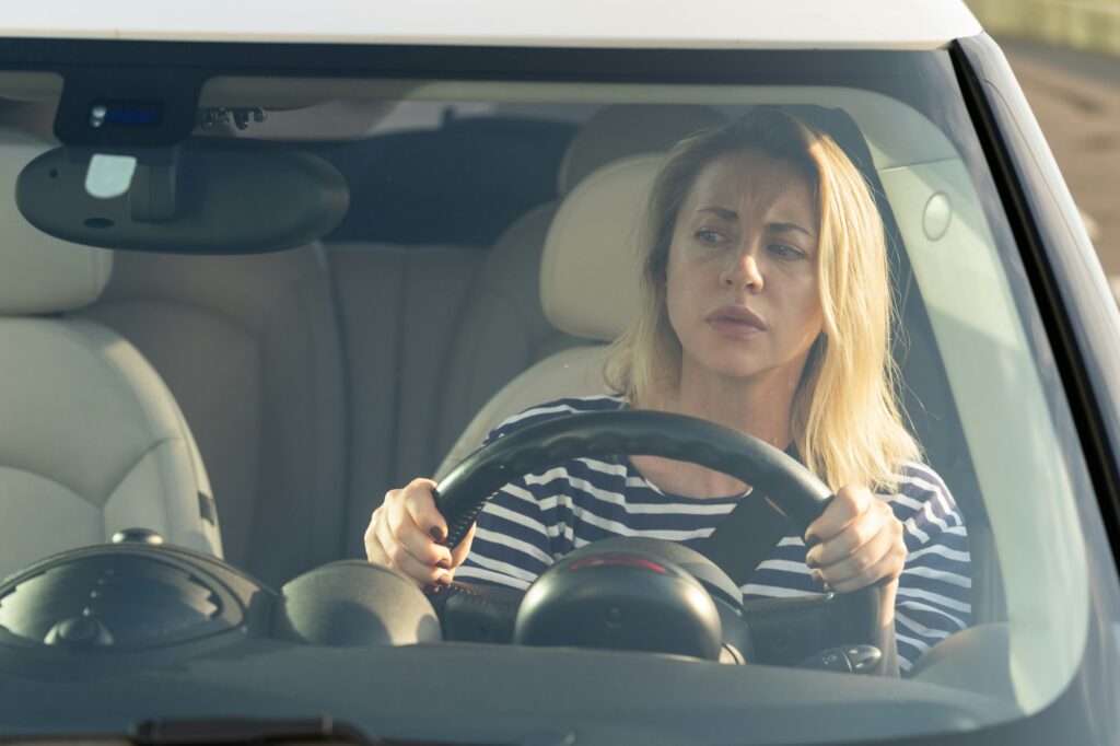 Anxious scared woman driver worried looking at car accident on road through windshield drive vehicle