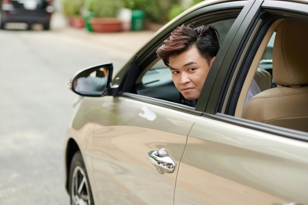 Jeune homme en situation de stationnement de sa voiture.